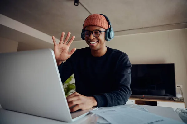 Homem afro-americano sorrindo e acenando para os funcionários durante uma reunião on-line em um laptop. Homem afro-americano feliz trabalhando remotamente em casa. Foto de alta qualidade — Fotografia de Stock
