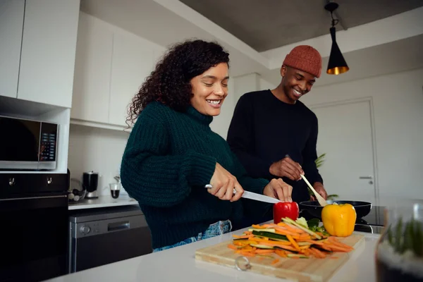 Young mixed race couple cooking food in the kitchen at home. Happy couple preparing food and smiling. High quality photo — Stock Photo, Image