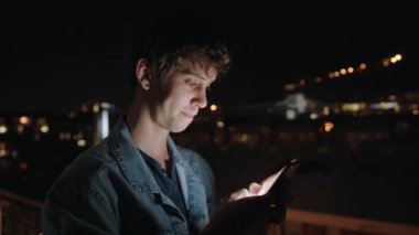 Caucasian male texting partner on cellular device at night smiling getting excited 