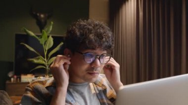Mixed race male working from home wearing spectacles typing on laptop engaging in video call 