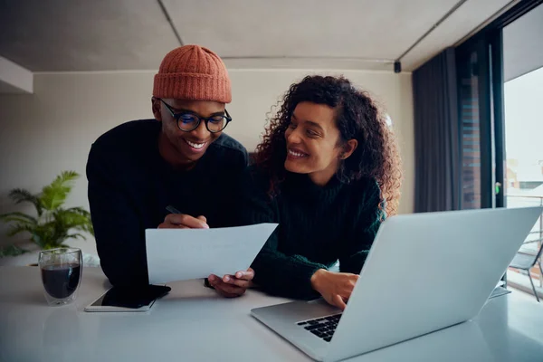 Primer plano de la pareja de razas mixtas utilizando el ordenador portátil para la banca en línea. Feliz pareja afroamericana sonriendo y mirándose mientras trabajan juntos en casa. Foto de alta calidad — Foto de Stock