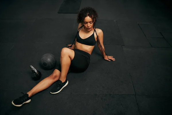 Atleta afro-americana descansando após um treino intenso no ginásio. Mulher afro-americana segurando corda pulando. Foto de alta qualidade — Fotografia de Stock