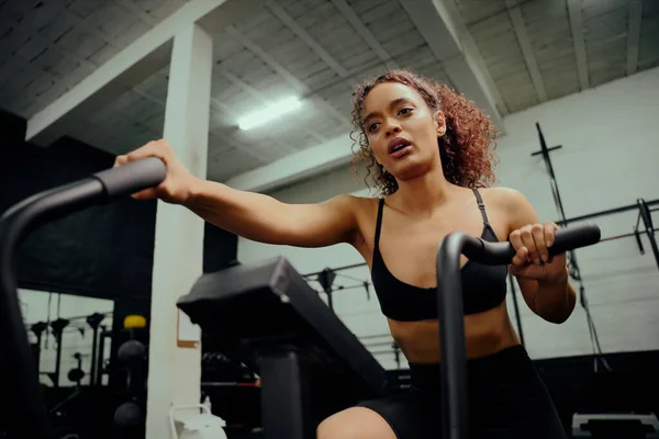 在交叉训练中使用椭圆教练的非裔美国女性。女运动员在体育馆里锻炼。高质量的照片 — 图库照片