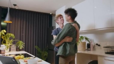 Happy romantic male couple bonding in kitchen dancing together showing affection