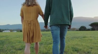 Mixed race romantic couple walking through grass romantically 