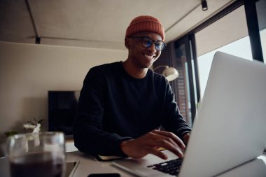Evde çalışan ve dizüstü bilgisayarında yazan Afro-Amerikan erkek. Afrika kökenli Amerikalı erkek evden çalışmak için elektronik aletleri kullanıyor. Yüksek kalite fotoğraf