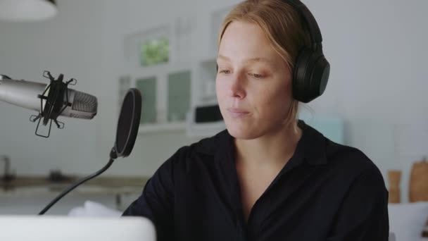 Blanc femelle podcaster enregistrement épisode de la maison portant des écouteurs et parler dans le microphone — Video