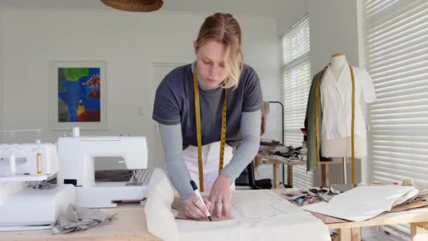Kaukaska projektantka pracująca od domu pisząc pomiary w dół projektując sukienki — Wideo stockowe