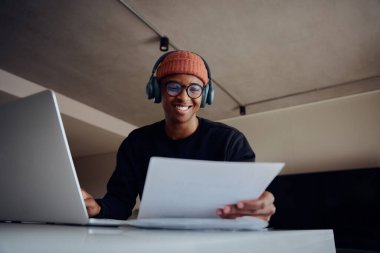 Evde dizüstü bilgisayar kullanarak çalışan Afro-Amerikan erkek. Memleketten sıkı çalışırken elinde kağıt tutan mutlu Afrikalı Amerikalı erkek. Yüksek kalite fotoğraf 