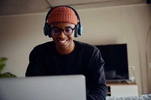 Homem afro-americano trabalhando em casa usando laptop. Homem afro-americano feliz trabalhando em casa com fones de ouvido. Foto de alta qualidade — Fotografia de Stock