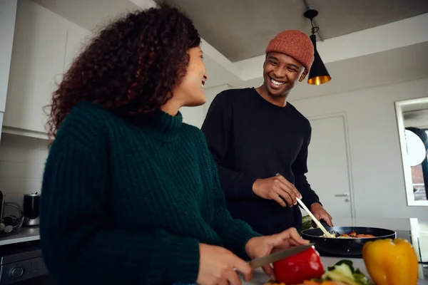 Young mixed race couple cooking food in the kitchen at home. Happy couple preparing food and smiling at each other. High quality photo — Stock Photo, Image