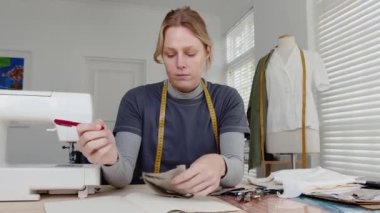 Beyaz kadın moda tasarımcısı not defterine yazı yazan kadın için kıyafet yapıyor.