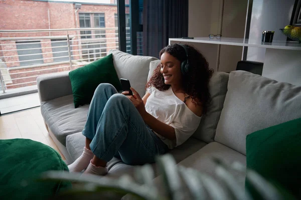 Raça mista adolescente relaxante em casa mensagens de texto no dispositivo celular — Fotografia de Stock