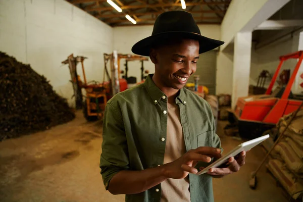 Agriculteur afro-américain mâle tapant sur tablette numérique debout dans hangar — Photo