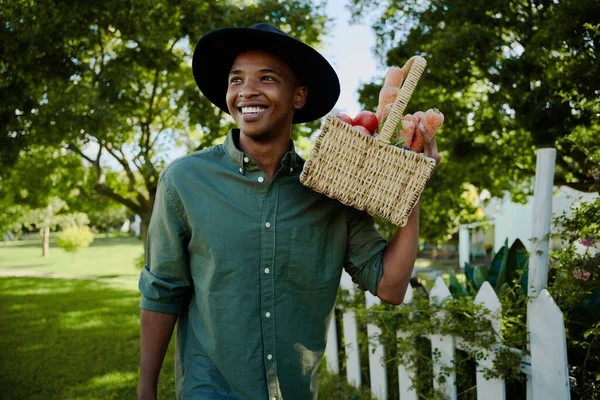 Mixed race male farmer walking outdoors holding vegetables basket — Stock Photo, Image