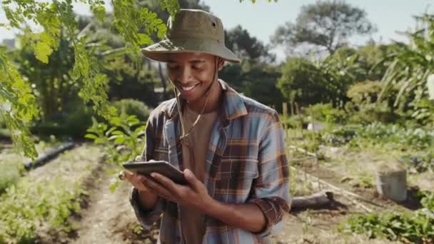 Mixte race mâle agriculteur debout dans le jardin dactylographier sur tablette numérique — Video
