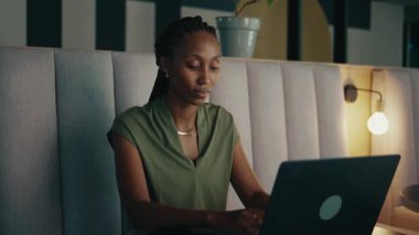 Modern ofis lobisindeki işi tamamlamak için dizüstü bilgisayar kullanan yorgun siyah iş kadını.