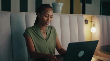 Modern ofis salonunda dizüstü bilgisayarla çalışan, zeki, genç bir iş kadını.