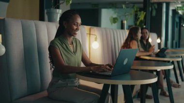 Modern ofis lobisinde dizüstü bilgisayarda çalışan mutlu bir iş kadını.