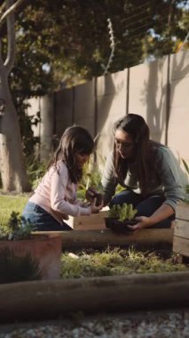 Bahçede annesine yardım eden etnik kökenli bir Asyalı kız. Yüksek kaliteli FullHD görüntüler