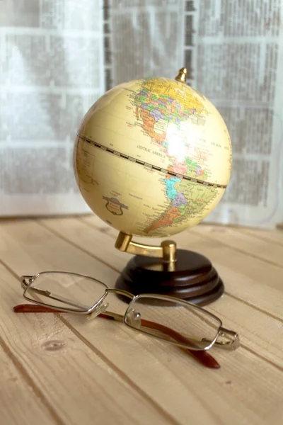 small globe and glasses are on the table