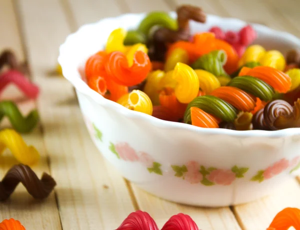 Pâtes multicolores couchées sur une table en bois — Photo