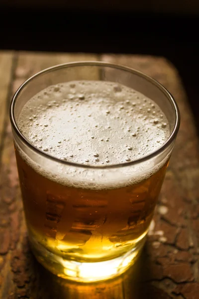 Glass of light beer on a dark pub. — Stock Photo, Image