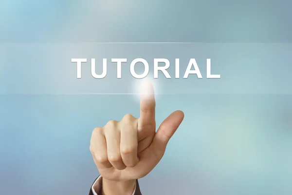 Business hand clicking tutorial button on blurred background — Stock Photo, Image