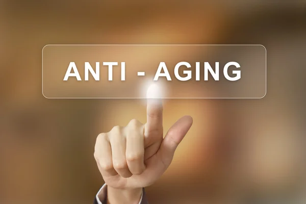 Negócio mão clicando botão anti envelhecimento no fundo borrado — Fotografia de Stock