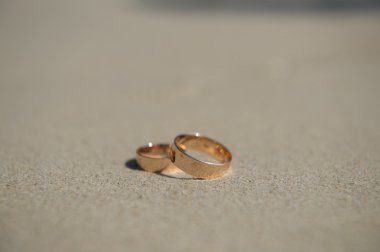 wedding rings on sea sand washed by the waves clipart