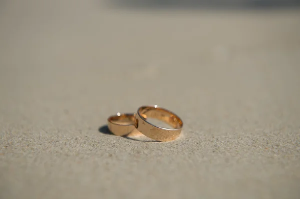 Anéis de casamento na areia do mar lavados pelas ondas — Fotografia de Stock