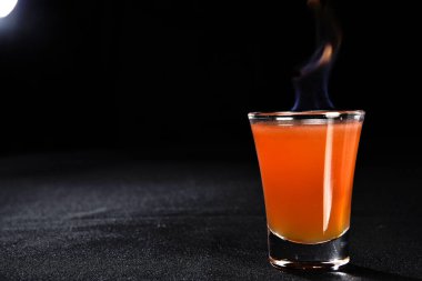 Böğürtlenli, buzlu ve cinle ferahlatıcı alkollü içecek, arka planda bulanık duran cam bardakta servis edilen limon kabuğu.