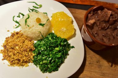 Brezilya fasulyesi ve domuz fiyodası, pirinç unu salatası ve bulanık ahşap parçaları.