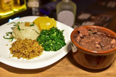 Brezilya fasulyesi ve domuz fiyodası, pirinç unu salatası ve bulanık ahşap parçaları.