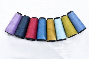 Beyaz arkaplanlı birkaç makara dikiş ipliği