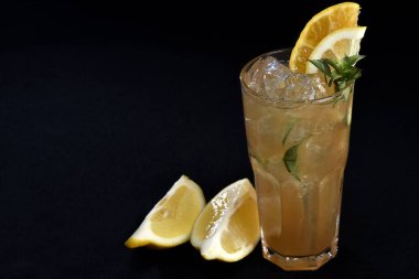 Böğürtlenli, buzlu ve cinle ferahlatıcı alkollü içecek, arka planda bulanık duran cam bardakta servis edilen limon kabuğu.