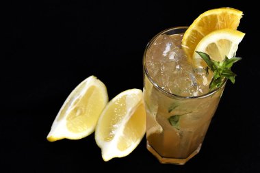 Böğürtlenli, buzlu ve cinle ferahlatıcı alkollü içecek, arka planda bulanık duran cam bardakta servis edilen limon kabuğu.