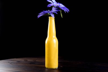 Siyah arka planda kırmızı çiçekli mavi şişe.