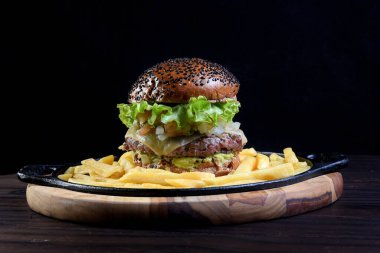 Peynirli, salatalı, turşulu ve siyah arka planda izole edilmiş susamlı burger..