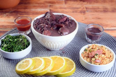 Tipik Brezilya yemekleri fasulye, domuz pastırması, lahana, pirinç, salata, baharat ve biberli sosis..