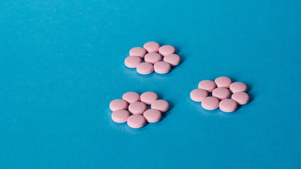 Розовые таблетки на синем фоне — стоковое фото