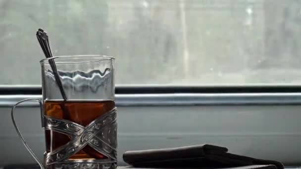 Ukrayna demiryolu. Kompartımandaki masada geleneksel bir fincan tutacağında çay var. Bardaktan çay poşeti çıkaran bir elin yakın çekimi. Çay yap. Yolculuk. — Stok video