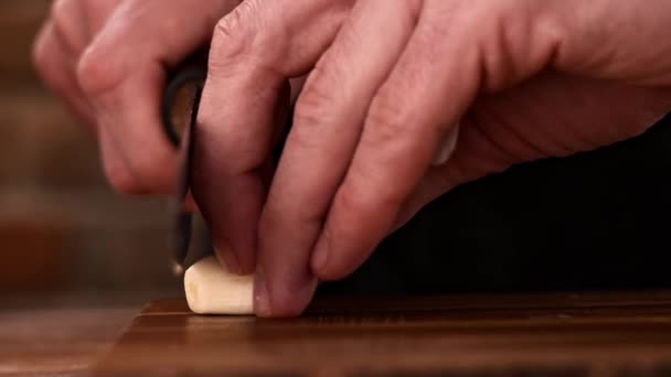 Cortar el ajo en rodajas pequeñas con un cuchillo en una tabla de madera — Vídeos de Stock