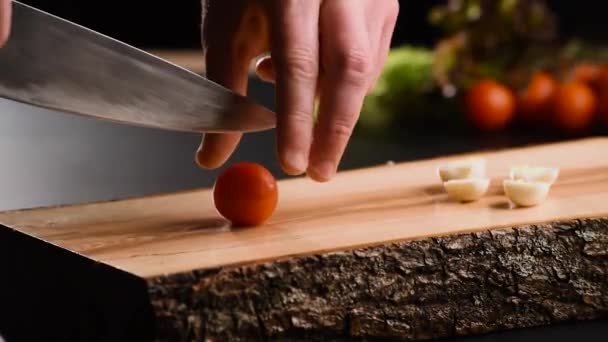 Η ντομάτα κόβει από κοντά. Ο σεφ κόβει την τομάτα. Μαχαίρι, ξύλο κοπής, ντομάτα κεράσι. Δαχτυλίδι από ντοματό.Το χέρι του μάγειρα. Κόψτε λαχανικά για σαλάτα. Υγιεινή τροφή. Κοντινό πλάνο. Μακρό — Αρχείο Βίντεο