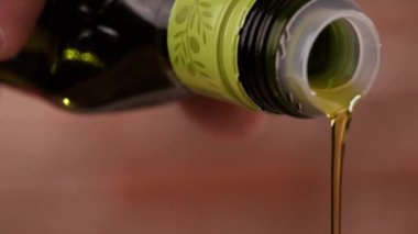 Şişeden siyah arka planı olan gümüş bir tencereye Macro yağı dökülüyor..