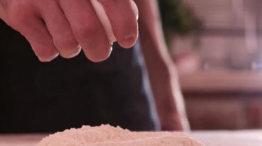 Unun içine düşen yumurta. Erkek ellerinin un üzerinde çiğ yumurta kırmasını, pişirme konseptini yakından izleyin.