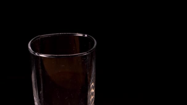 Verre vide avec glaçons sur fond noir. Glace tombant dans un verre vide sur fond noir, au ralenti. — Video