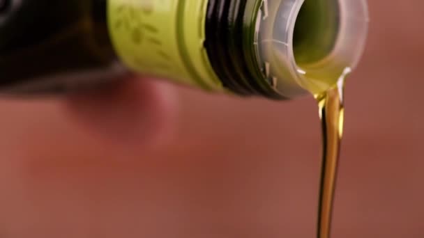 Macro shot van olie wordt gegoten uit een fles in een zilveren pot met een zwarte achtergrond. — Stockvideo