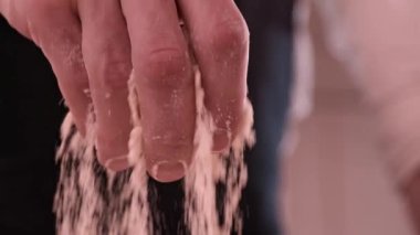 Fırıncının yakın çekimi mutfağa un döker. Başla. Fırıncı fırına bir tutam un serpiyor. Profesyonel fırıncı ve aşkla pişirme