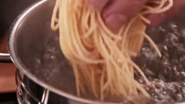 Lezzetli İtalyan makarnası. Erkeklerin kaynayan suya çiğ makarna koyarken yakın plan çekimleri. Restoranda yemek pişirmek.. 